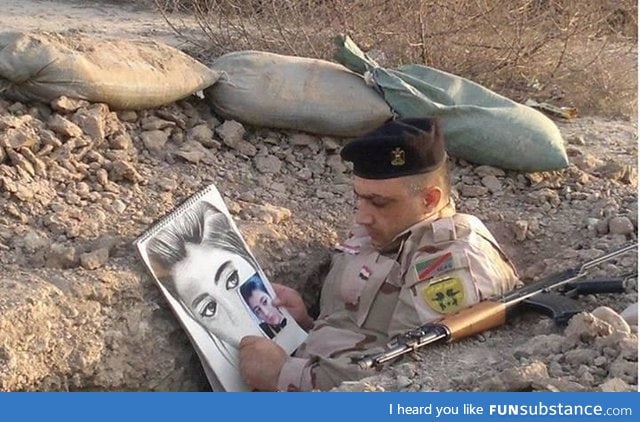 An Iraqi soldier passes time in a foxhole