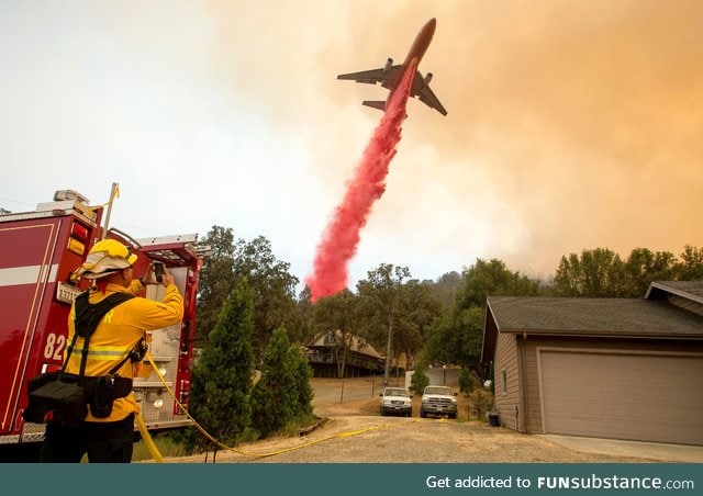 "An air tanker drops fire retardant on flames as firefighters continue to battle