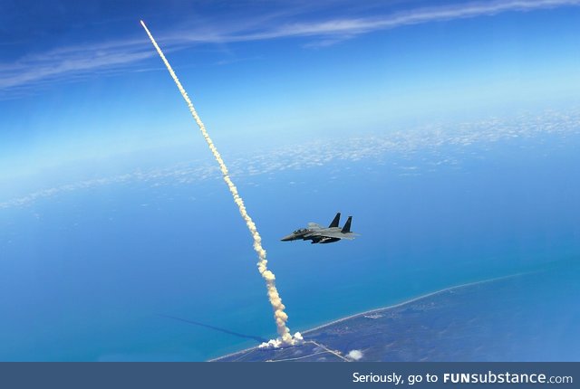 An F-15E patrols Kennedy Space Center as the Space Shuttle Atlantis launches