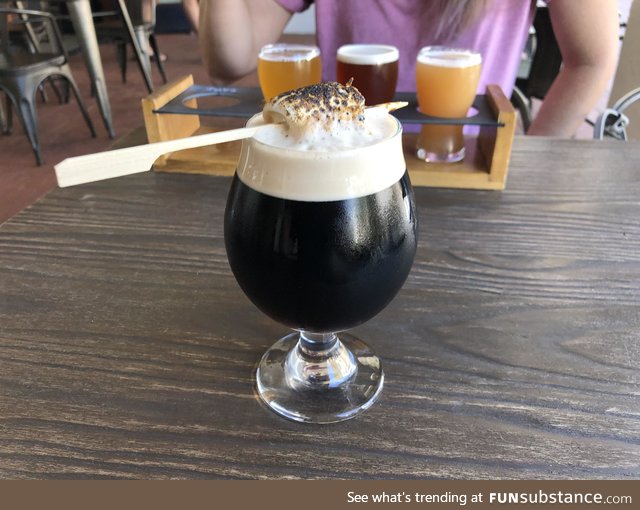 A s’mores porter with a burnt marshmallow stuck in it