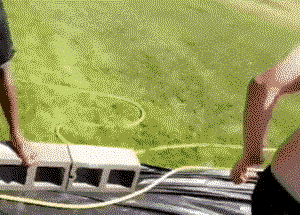 Guy attempts to slip-n-slide down a hill STANDING UP