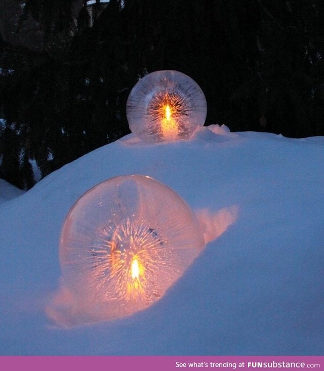 Water balloons half frozen with candles placed in the hollow center