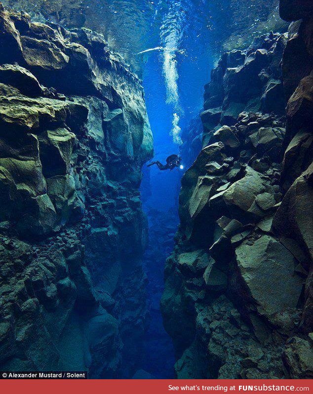 An amazing photograph of a scuba diver between two tectonic plates