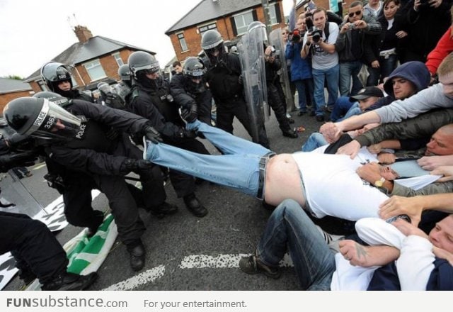 Police and rioters together help fat man get out of trousers