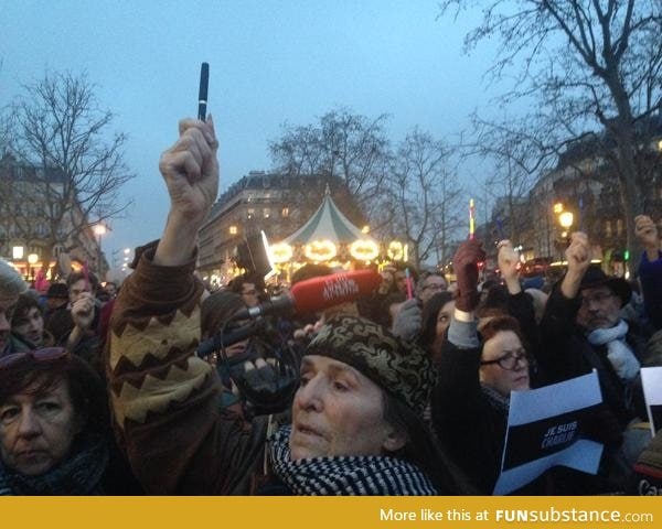 People holding pens in the air at a gathering in Paris to show support
