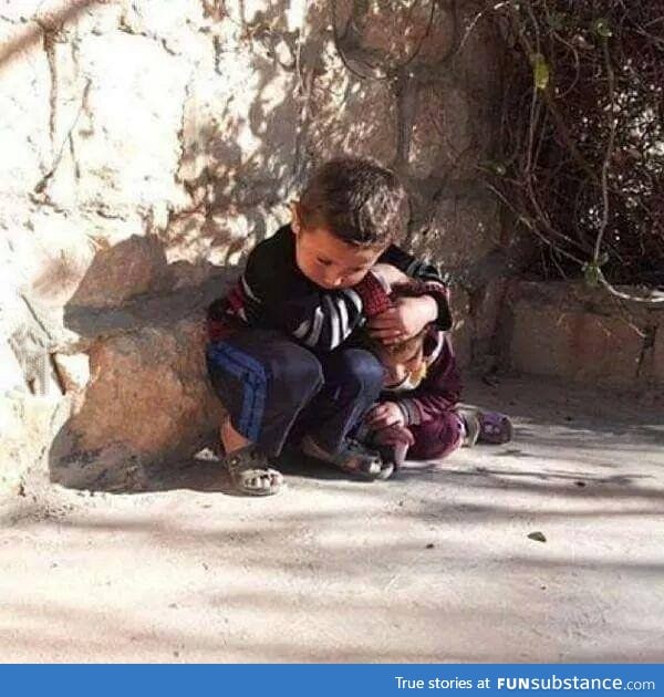 Syrian child trying to protect his sister from bombing