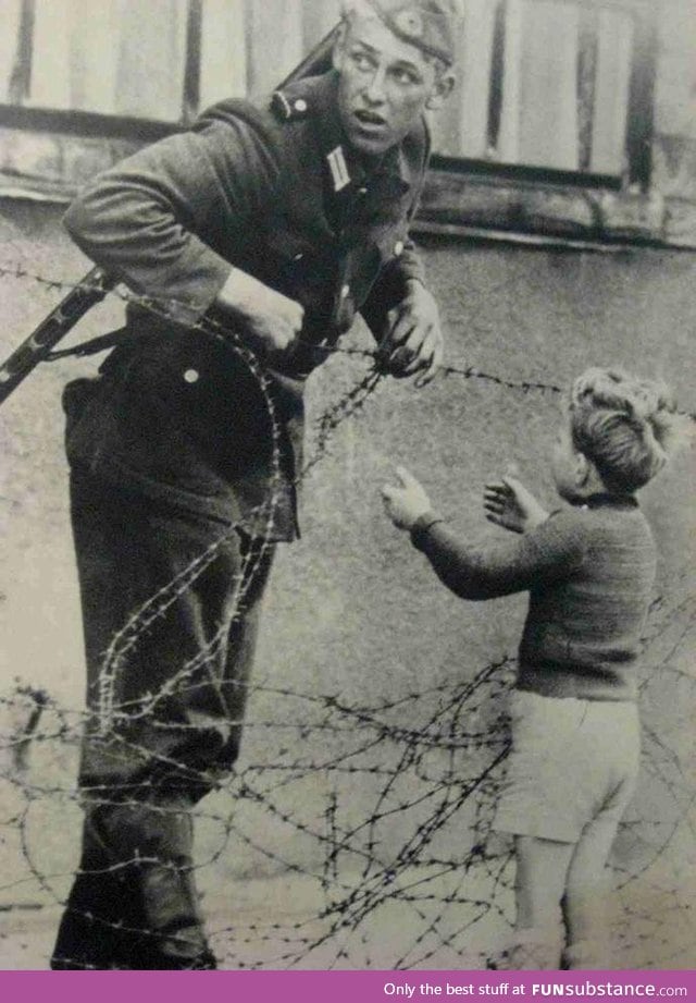 This moment.. An East German soldier ignores orders to let no one pass and helps a boy