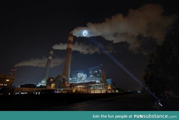 A sick child's face projected onto a factory smoke stack in China