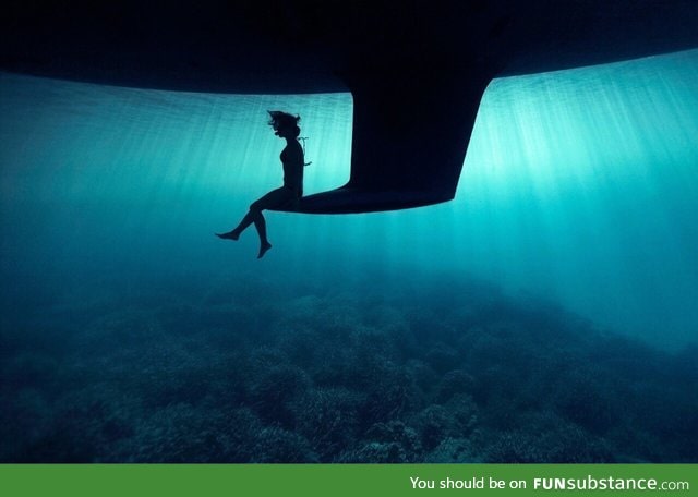 Just a girl sitting on the keel of a boat underwater