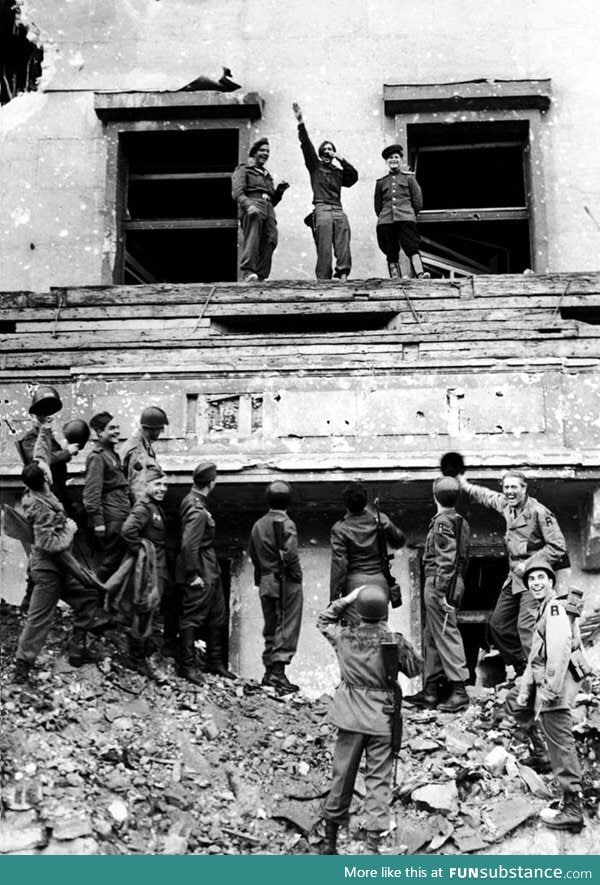 Allied American and Soviet troops imitate Hitler on a balcony after the defeat of Germany