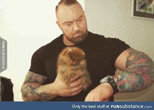 This very large man has a very little puppy and it's adorable.