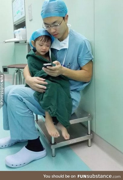 Cardiac surgeon comforts a weeping 2-year-old girl by playing cartoons before her surgery