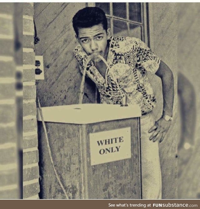 Stylish black man takes a sip from a "whites only" water fountain, 1960s