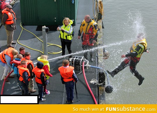 Kids playing with a water hose during coast guard demonstration