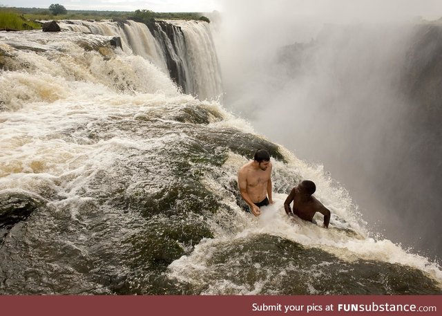 Two guys sitting near the edge of the Devil‘s Pool, Victoria Falls, Zambia