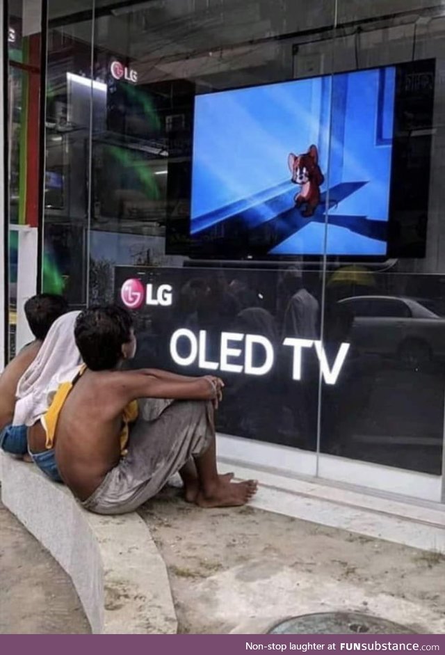 Shop owner in India playing cartoons on storefront display TV for kids to watch