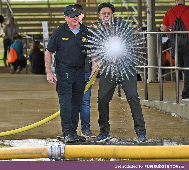 This student starting a firehose and a photo being taken at the exact moment. That water