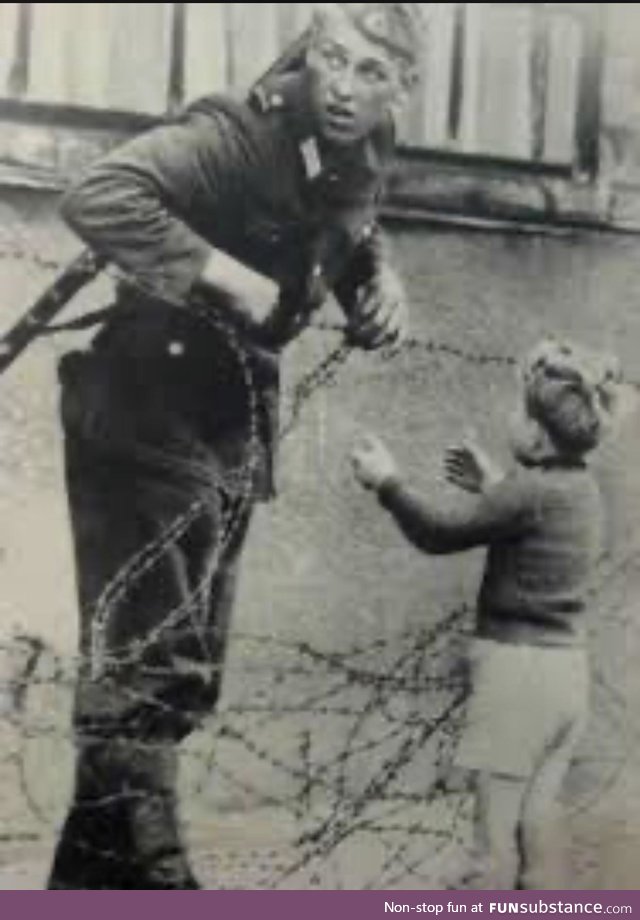 East German soldier letting boy through to reunite with his family