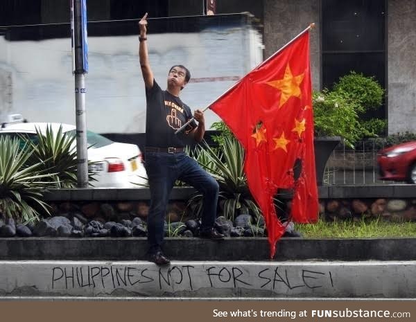 Filipino giving the finger to the Chinese embassy while burning their flag