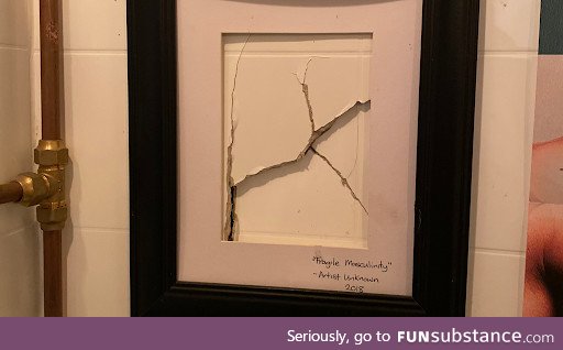 A bar's bathroom has a framed a punch in the wall, titled "fragile masculinity"