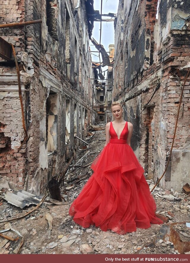A graduate in her graduation dress on the rubble of her school destroyed by the Russian