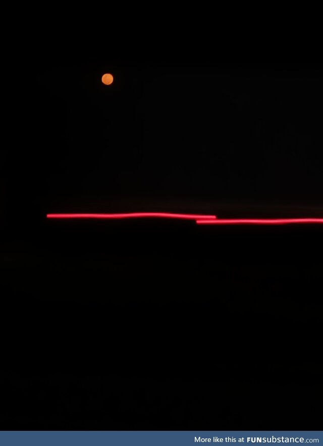 Orange-ish moon above a moving truck's light making it look like it was a drawing