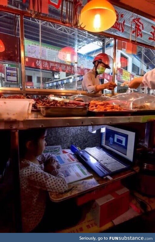 Chinese kid taking online class under her parents’ street food stand