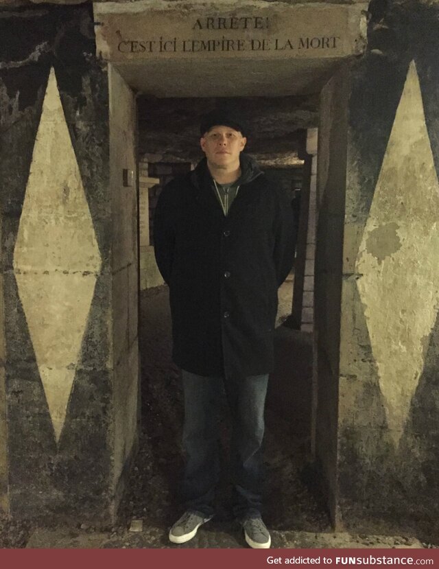 Me standing at the entrance to the Paris Catacombs. It says “Stop! This is the Empire