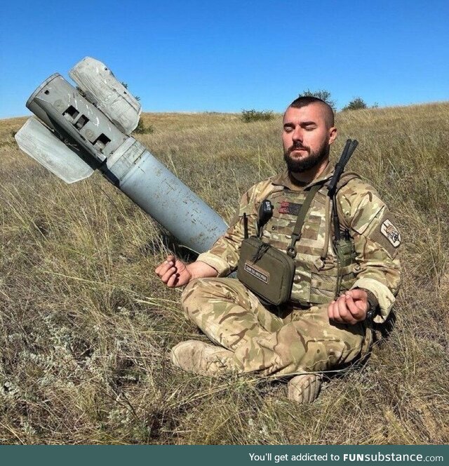 Ukrainian soldier meditating beside a missile