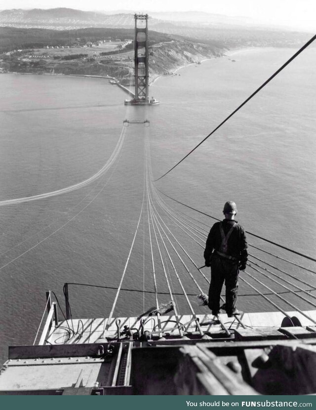 A man poses on the first cables during construction of the Golden Gate Bridge, 1935