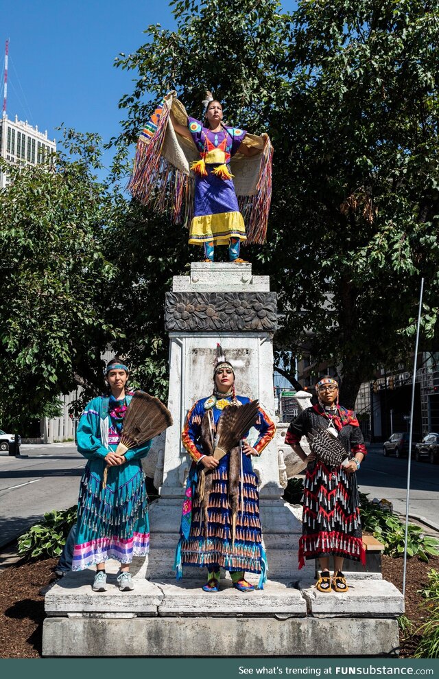 Indigenous women in traditional regalia stand over a former monument to Columbus in