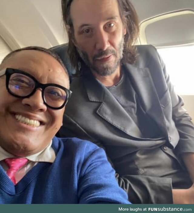 Keanu Reeves flying on economy class next to a fan grasping this opportunity by getting a