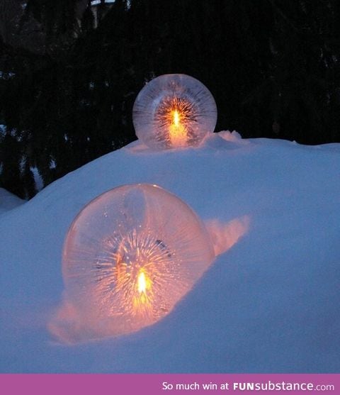 Water balloons half frozen with candles placed in the hollow center