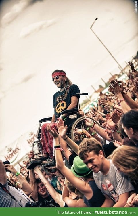 An old Hippie Crowd Surfing in His Wheelchair