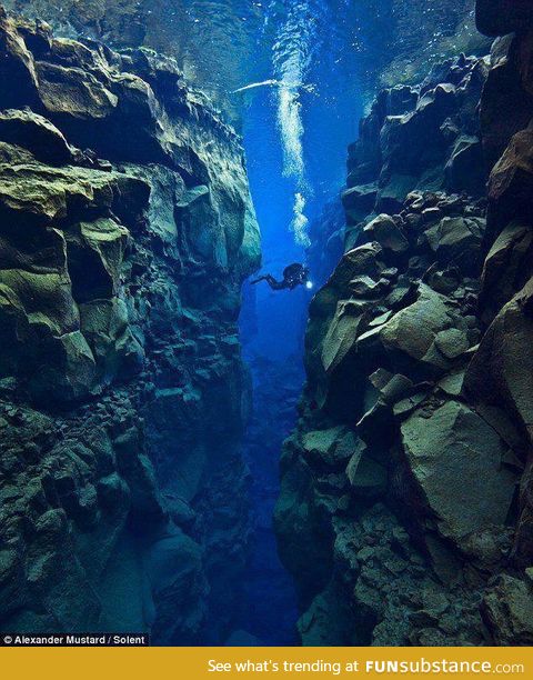 An amazing photograph of a scuba diver between two tectonic plates