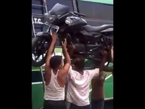 Guy carries a motorcycle up a ladder