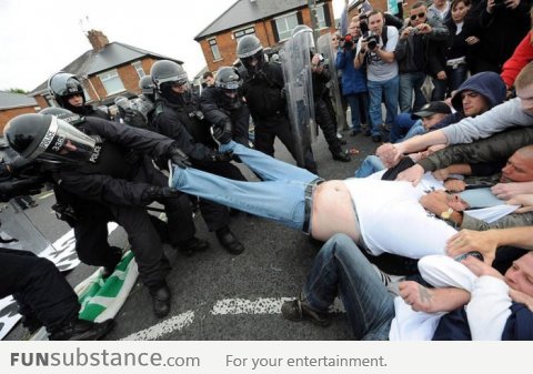 Police and rioters together help fat man get out of trousers