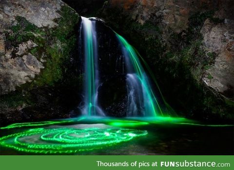 Long exposure shot of glowsticks dropped into a waterfall