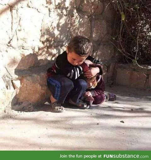 Syrian child trying to protect his sister from bombing