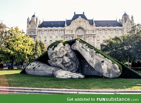 A giant sculpture crawls out of the ground in public square of budapest