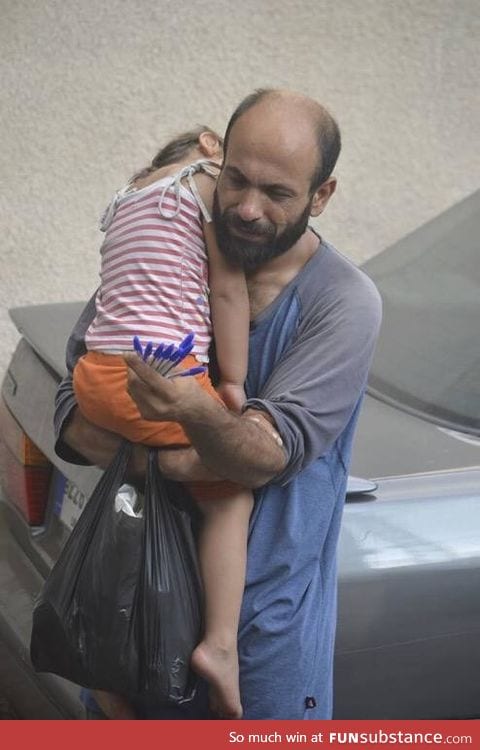 A Syrian father selling pens in Beirut while holding his sleeping daughter