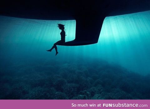 Just a girl sitting on the keel of a boat underwater
