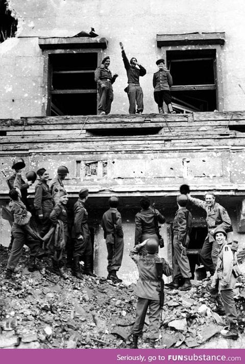 Allied American and Soviet troops imitate Hitler on a balcony after the defeat of Germany