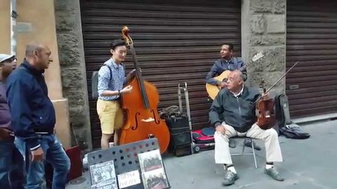 A tourist joins street musicians to play a beautiful music