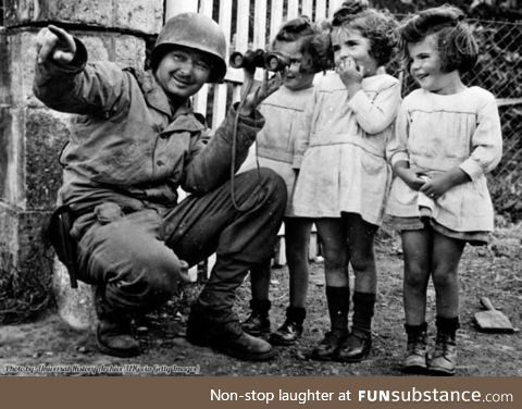 US soldier shares his binoculars with three little girls after the liberation of Normandy