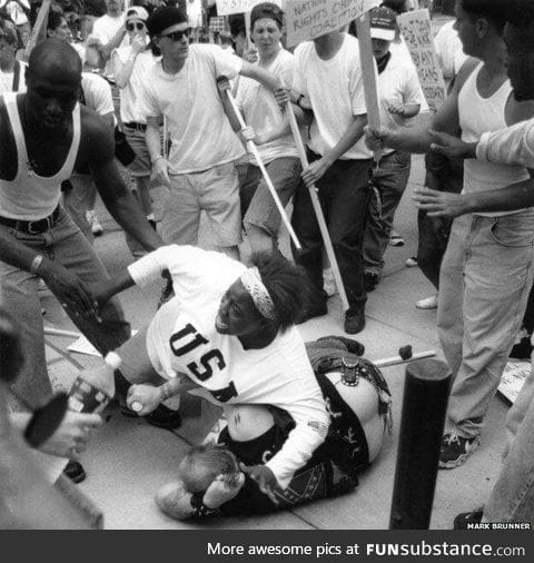 Black woman protecting a fallen racist from a crowd