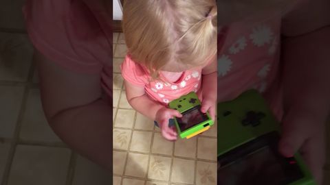 Little girl attempting to play a Game Boy Color in the age of touchscreen interfaces