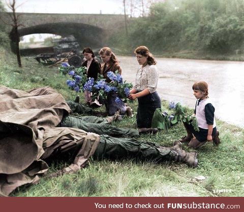 Russian women liberated from a slave labor camp lay flowers at the feet of three soldiers