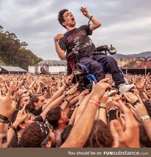 A guy in a wheel chair enjoys crowd surfing at a heavy metal festival in spain