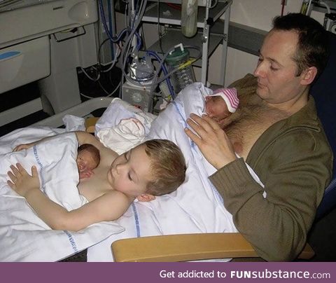 A big brother helping his father to give skin to skin contact to his premature twin